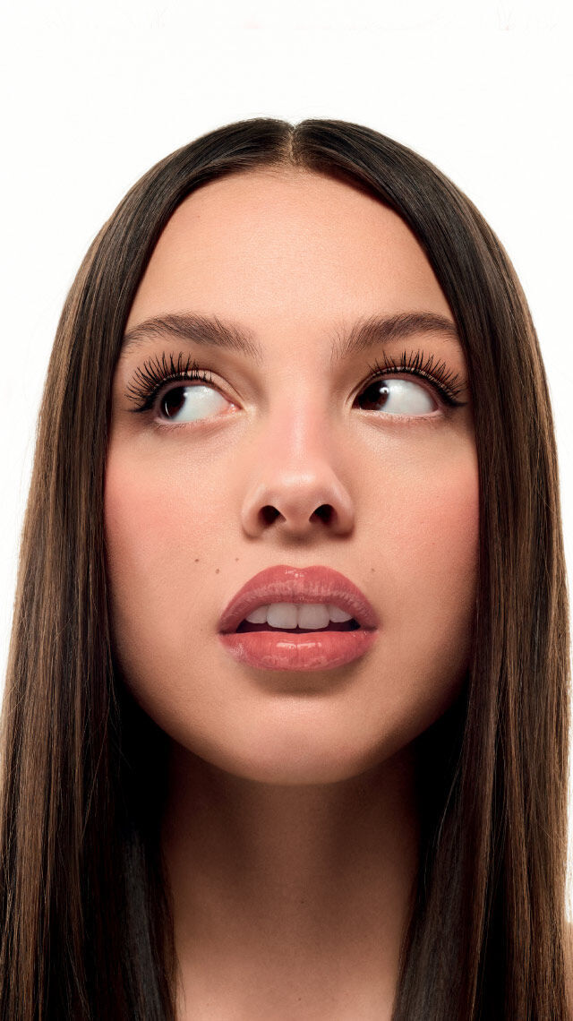 Image d'une jeune femme aux cheveux longs et lisses, regardant sur le cote avec un fond blanc.