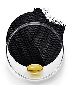 A clear petri dish containing a golden capsule is placed in front of a black brushstroke background.