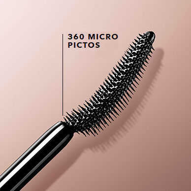 A close-up of a black mascara wand with a unique curved shape and short bristles, set against a soft beige background.