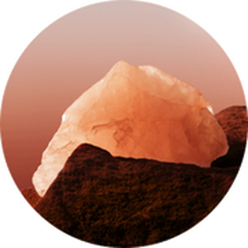 Un gros cristal de sel orange repose sur un terrain rocheux avec une lumiere douce au crepuscule.