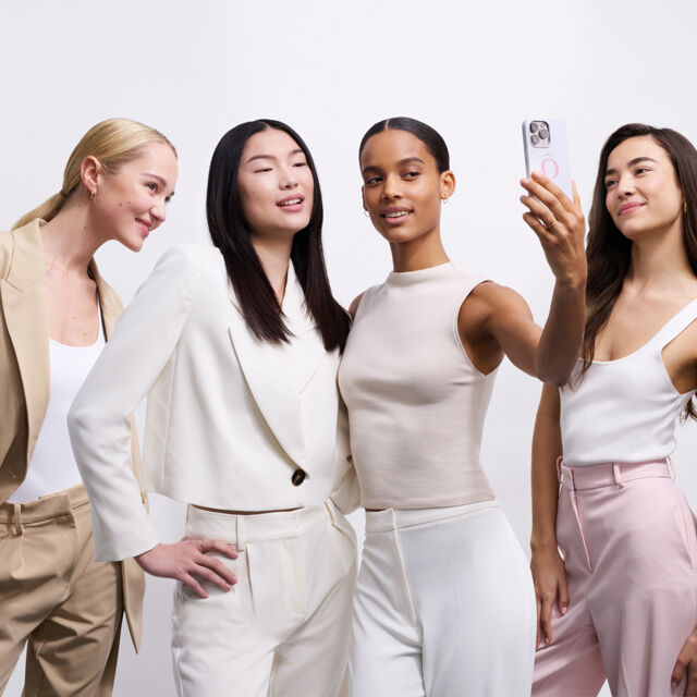 Vier vrouwen poseren samen voor een selfie, gekleed in stijlvolle, moderne outfits.