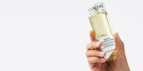 Un flacon de produit de soin de la peau de la marque Lancome, tenu dans une main.
