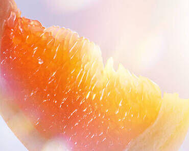 Close-up of a sliced peach with a soft, fuzzy texture and vibrant orange and yellow hues, illuminated by soft light.