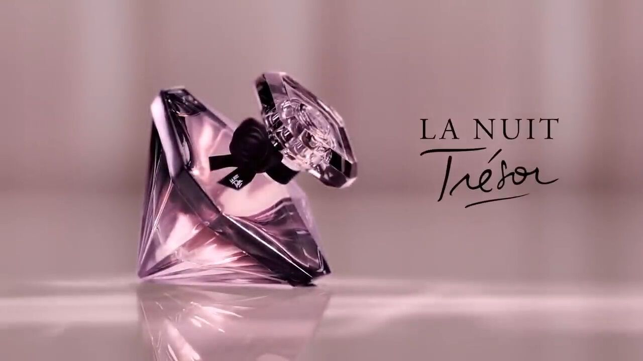 Flacon de parfum La Nuit Tresor, en forme de diamant, sur fond flou. Elegance et mystere.