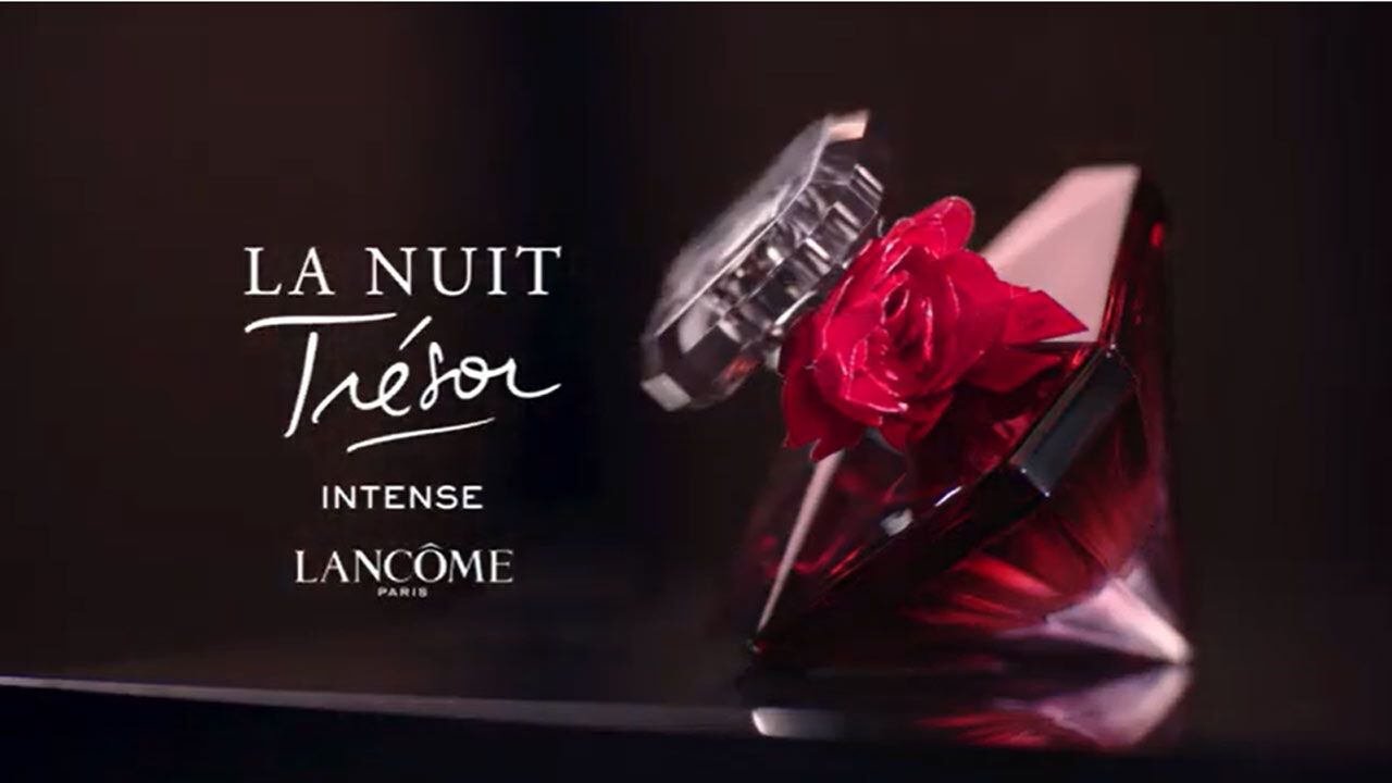 Flacon de parfum La Nuit Tresor Intense de Lancome, avec une rose rouge, sur fond sombre.