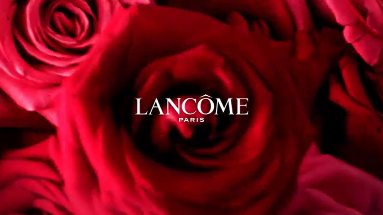 Un gros plan sur une rose rouge avec le logo de Lancome Paris en superposition, evoquant la beaute et le luxe.