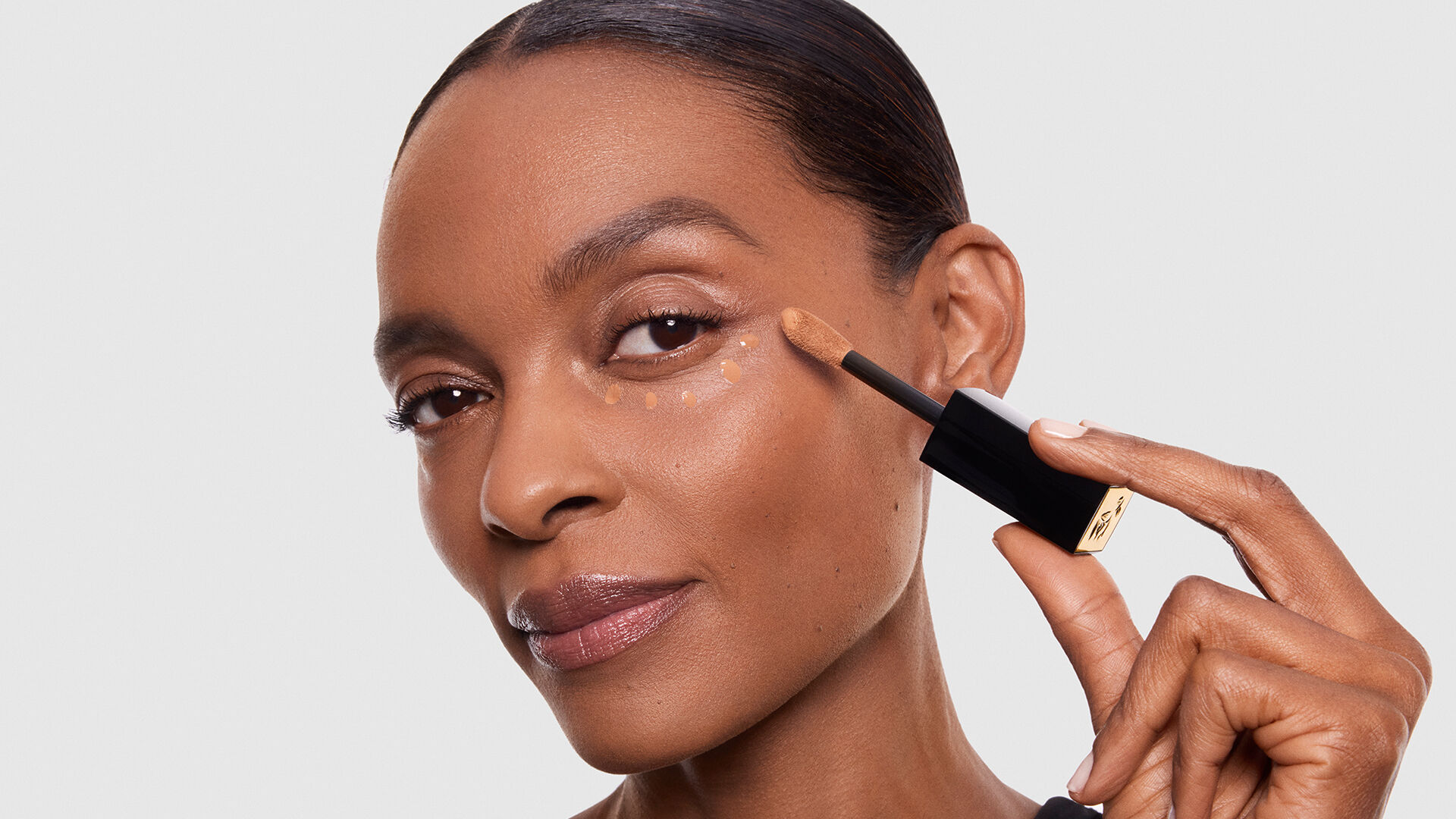 Een afbeelding van twee cosmetische producten van Lancome: een fles concealer en een fles foundation, beide met een minimalistisch ontwerp op een neutrale achtergrond.