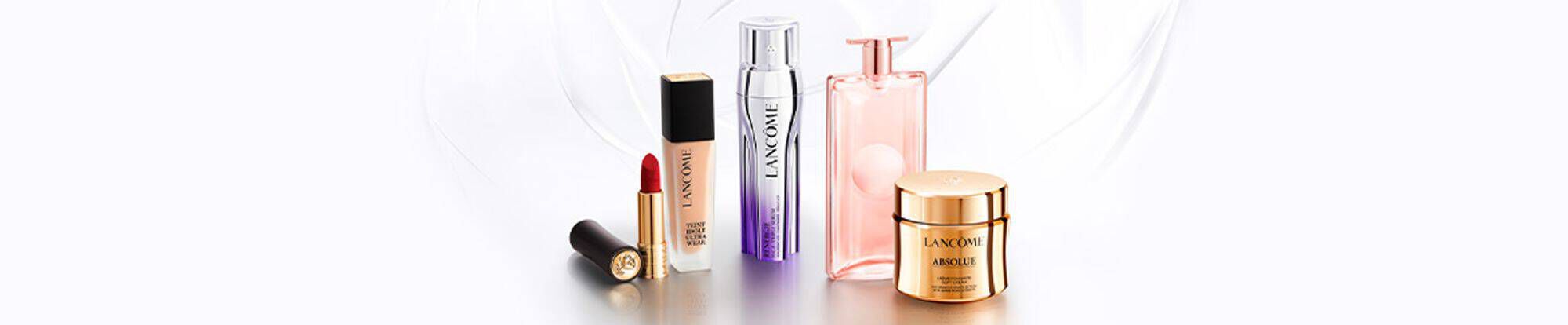 Een assortiment van Lancome-producten, waaronder een lipstick, een serum, een parfum en twee cremes, op een lichte achtergrond.