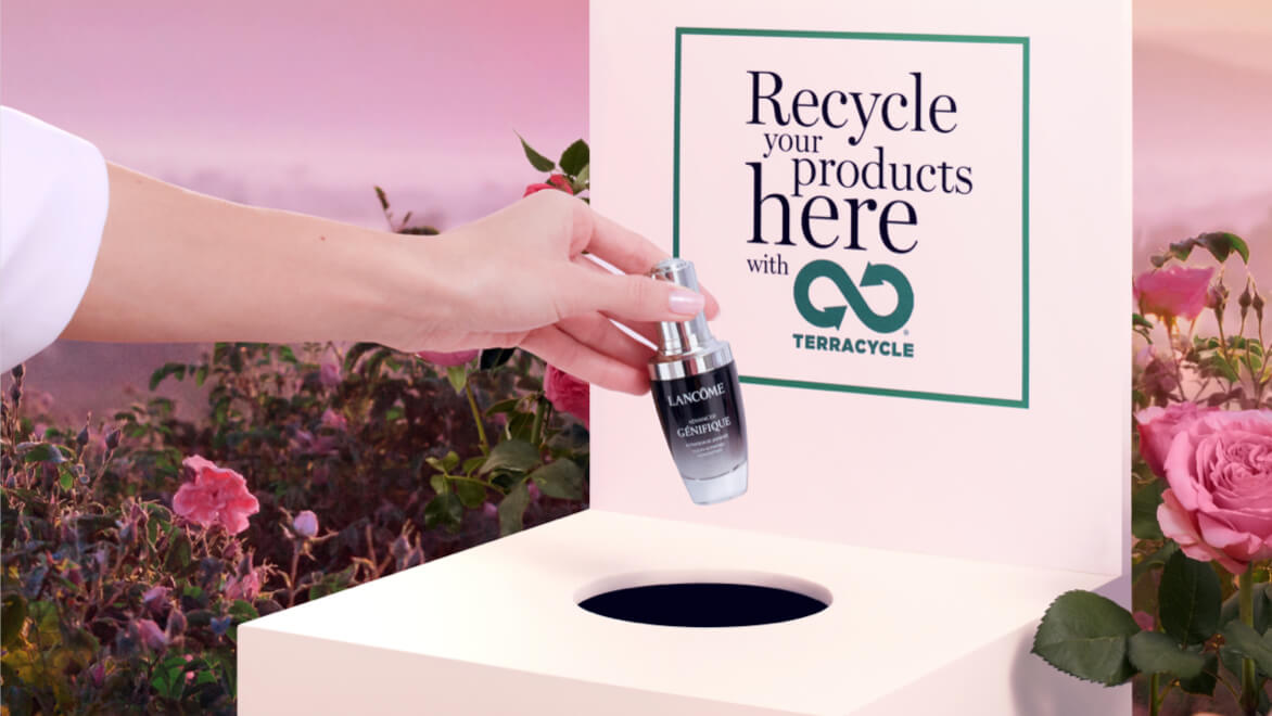Une main dépose un flacon de sérum dans une boîte de recyclage de Lancôme, entourée de roses.