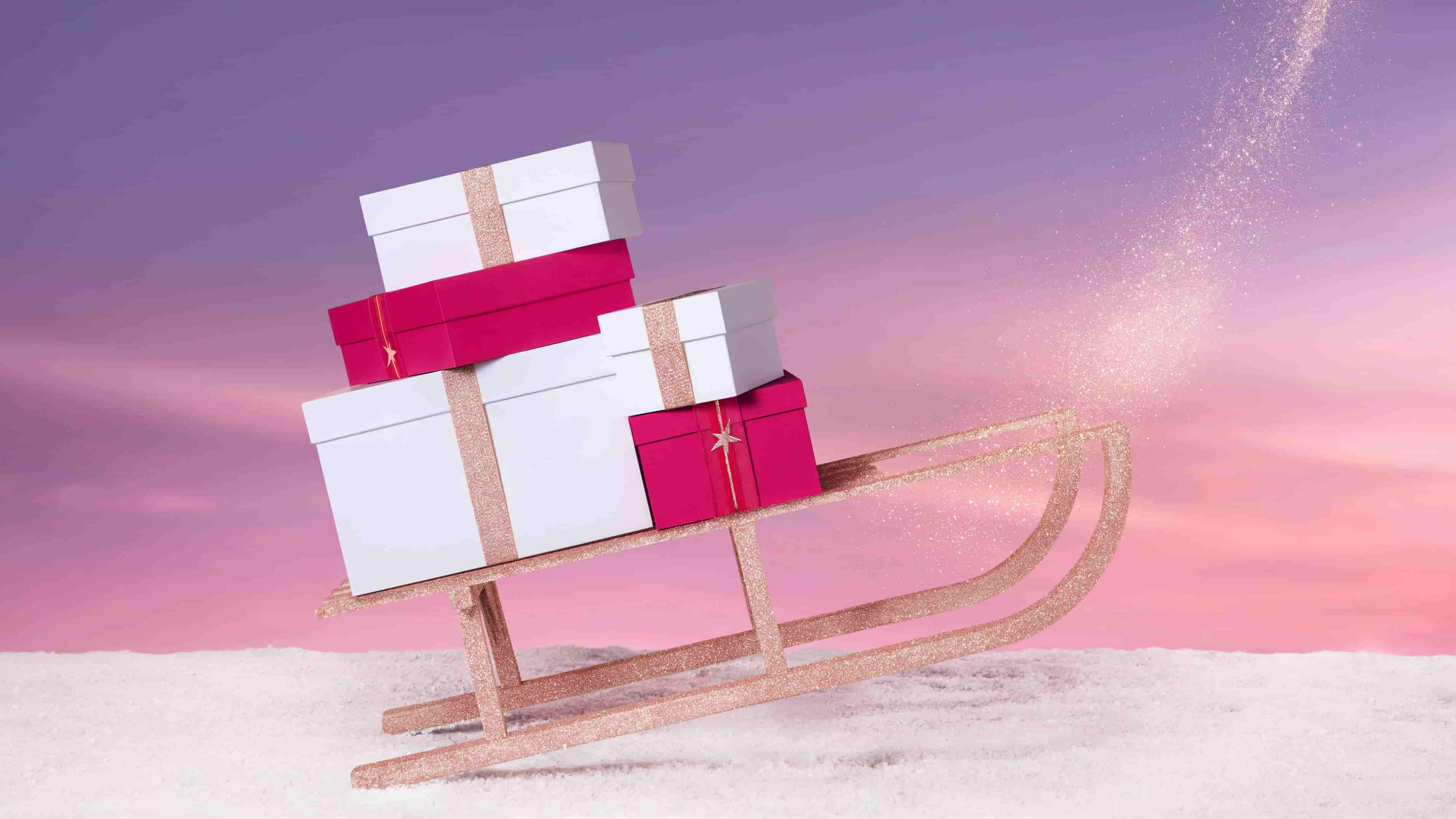 Un traîneau scintillant chargé de cadeaux colorés sur un fond de neige et de ciel aux teintes pastel.